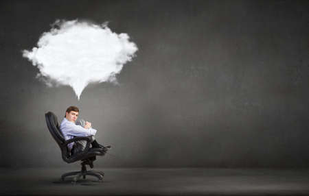 Young businessman sitting in chair and dreaming about somethingの写真素材