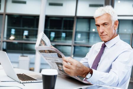 Businessman in office with newspaperの写真素材
