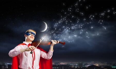 Young woman in super hero costume playing violinの写真素材
