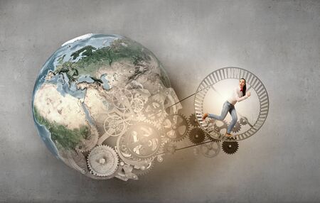 Young businesswoman running in wheel of gears mechanismの写真素材