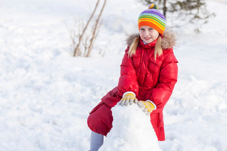 Cute girl of school age having fun in winter parkの写真素材