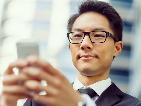 Businessman in city holding his mobileの写真素材