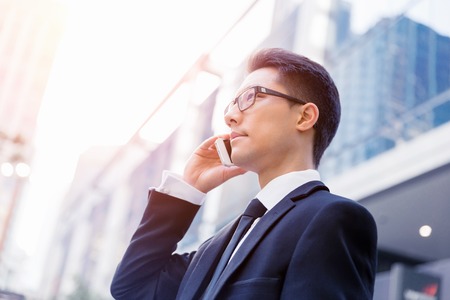Businessman in city holding his mobileの写真素材