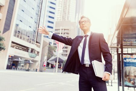 Businessman trying to catch a taxi in business cuty districtの写真素材