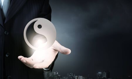 Close up of businessman holding yin yang symbols in palmの写真素材