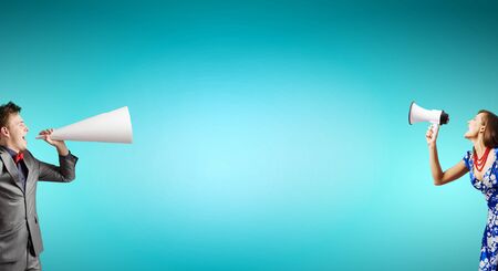 Two business people shouting in megaphones at each otherの写真素材