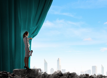 Young woman in business suit opening color curtain of stageの写真素材