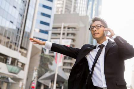 Businessman trying to catch a taxi in business cuty districtの写真素材