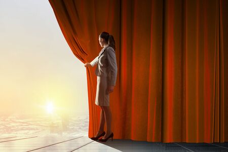 Young woman in business suit opening color curtain of stageの写真素材