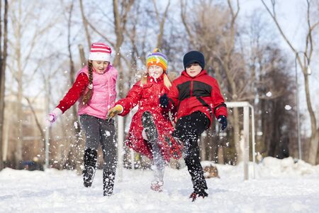 Cute children jumping and having fun in winter parkの写真素材