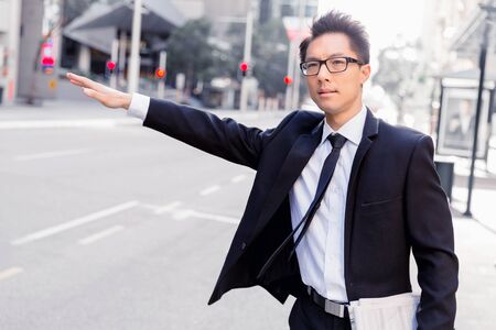 Businessman trying to catch a taxi in business cuty districtの写真素材