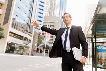 Businessman trying to catch a taxi in business cuty districtの写真素材