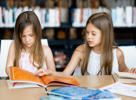 Little girls reading books in library