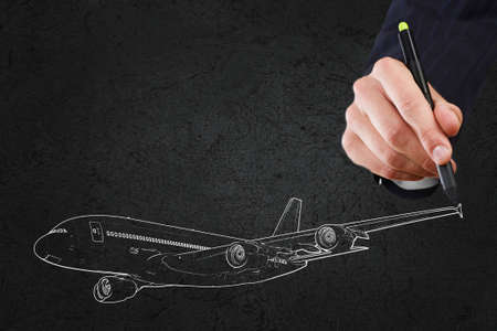 Close up of hand drawing airplane on black の写真素材