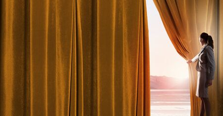 Young woman in business suit opening color curtain of stageの写真素材