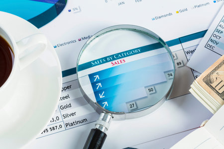 Magnifing glass and documents with analytics data lying on table