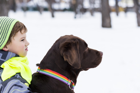 Kid of school age with dog in winter parkの写真素材
