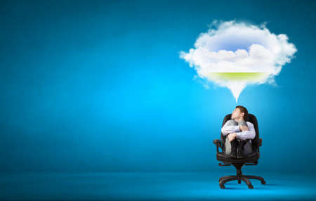 Young businessman sitting in chair and dreaming about somethingの写真素材