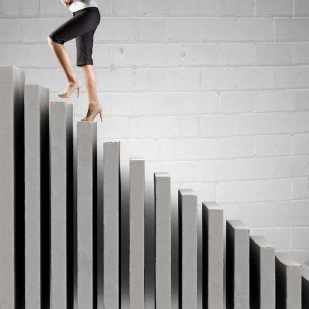 Young businesswoman walking up on staircase representing success conceptの写真素材