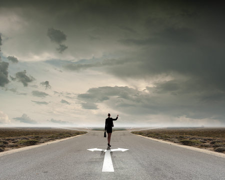 Back view of businesswoman standing on crossroads and making choiceの写真素材