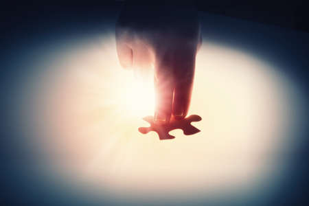 Close up of hands connecting puzzle element and making jigsaw completeの写真素材