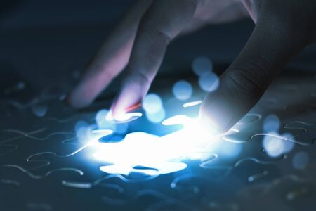 Close up of hands connecting puzzle element and making jigsaw completeの写真素材