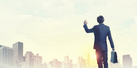 Rear view of businessman looking at sunset above cityの写真素材