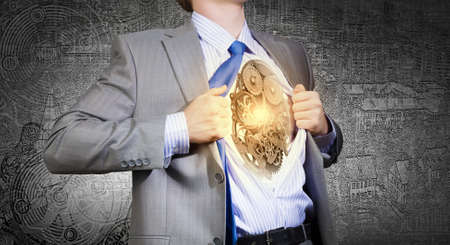 Young businessman in suit opening his chest and acting like super heroの写真素材