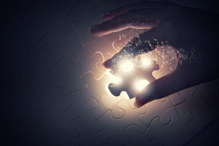 Close up of hands connecting puzzle element and making jigsaw complete