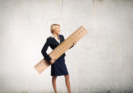 Young businesswoman measuring something with big rulerの写真素材