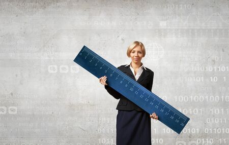 Young businesswoman measuring something with big rulerの写真素材