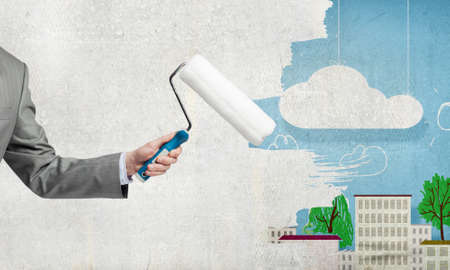 Close up of businessman hand painting wall with rollerの写真素材