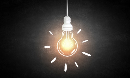 Illuminating hanging light bulb on dark backgroundの写真素材