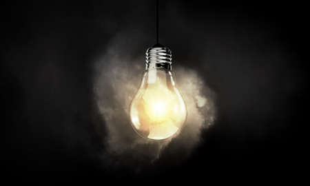 Illuminating hanging light bulb on dark backgroundの写真素材