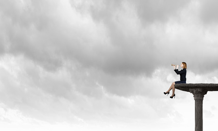 Young businesswoman in suit proclaiming something in hornの写真素材