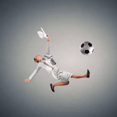 Full length businesswoman in jump kicking a soccer ballの写真素材