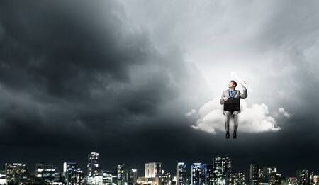 Young smiling businessman sitting with briefcase in handsの写真素材