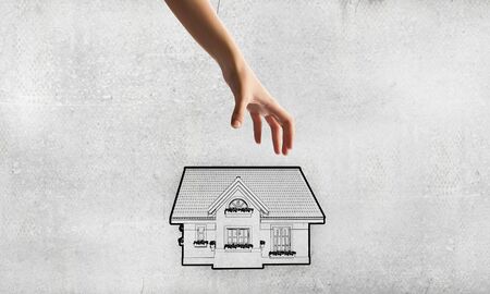 Human hand grabs drawn on paper houseの写真素材