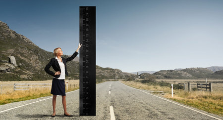 Young businesswoman measuring something with big ruler