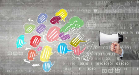 Close up of human hand holding megaphone with flying out announcementの写真素材