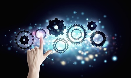 Close up human hand pointing at gears mechanismの写真素材