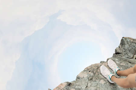 Close up of woman legs standing on the edge of rockの写真素材