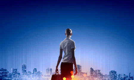 Rear view of businesswoman looking at night cityの写真素材