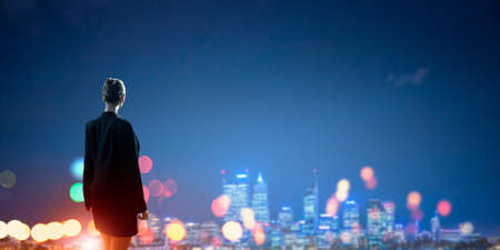 Rear view of businesswoman looking at night cityの写真素材