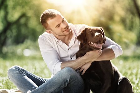 Young guy with retriever on walk in summer parkの写真素材