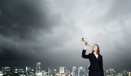 Young businesswoman in suit proclaiming something in hornの写真素材
