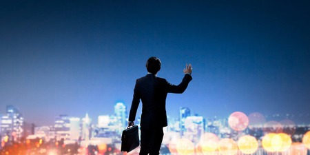 Rear view of businessman against night city gesturing with handの写真素材