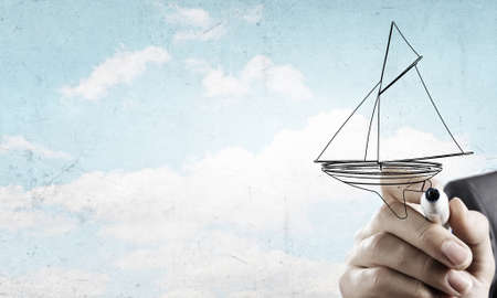 Close up of businessman hand drawing yacht with markerの写真素材