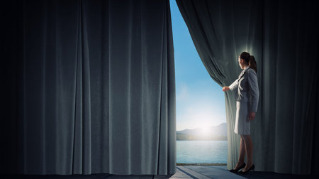 Young businesswoman opening stage curtain to another realityの写真素材