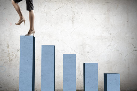 Young businesswoman stepping up on chart barの写真素材